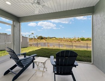 View from a screened-in lanai overlooking a peaceful pond and palm trees in The Villages, Florida—capturing the serenity homeowners want to return to, thanks to vigilant home care.