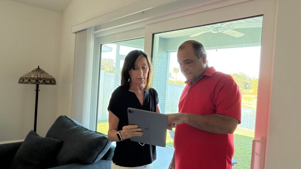 Sharon and Mark from In the Bubble Home Watch reviewing a client’s home inspection report on an iPad inside a Florida home.